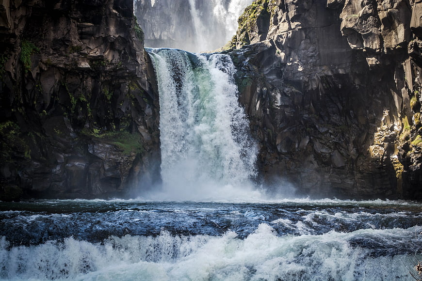 Powerful waterfall cascading into rushing river rapids