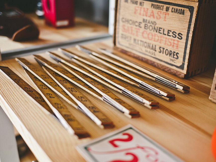 Vintage wooden rulers and antique codfish crate on table