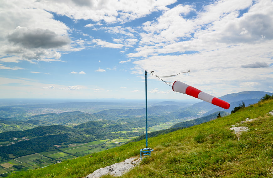 Red and white windsock on a grassy mountain peak