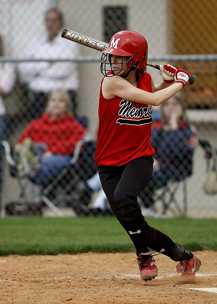 Female Softball Player Swinging Bat on Dirt Field