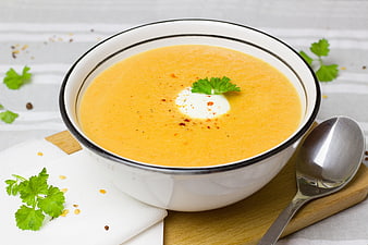 Creamy Carrot Soup in White Bowl with Cream and Parsley