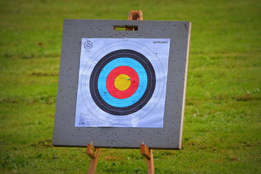 Archery target with arrows in the bullseye on a grassy field