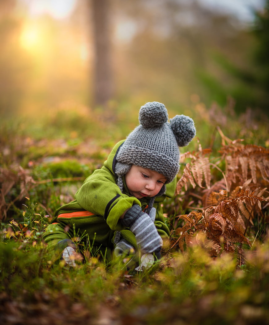 Toddler in Knit Bonnet Playing in Autumn Forest
