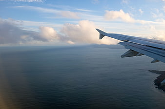 Airplane Wing View Over Ocean And Clouds