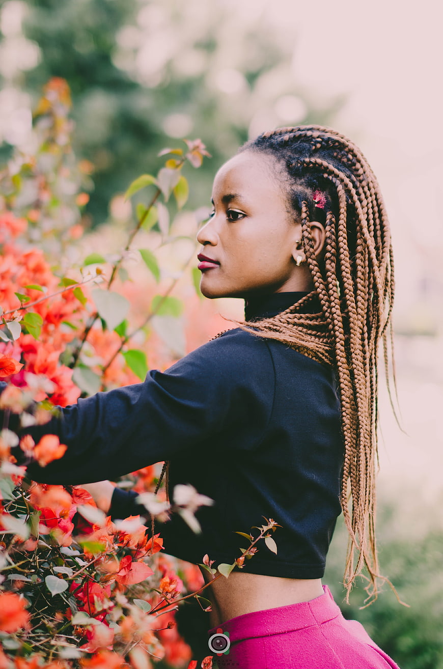 Portrait of woman with braids in garden with flowers