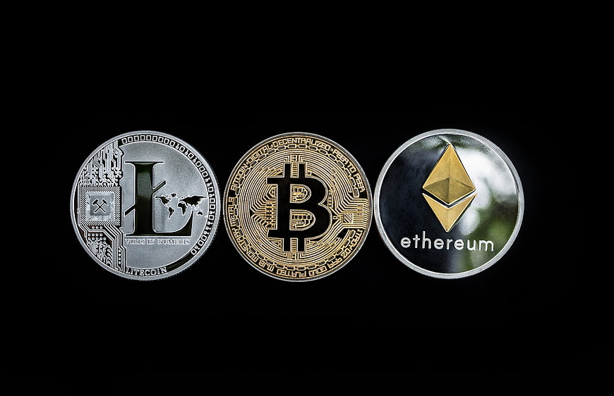 Physical Litecoin, Bitcoin, and Ethereum coins on black background