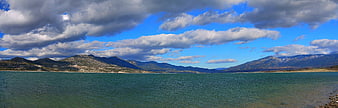 Panoramic view of a lake with mountains and cloudy sky
