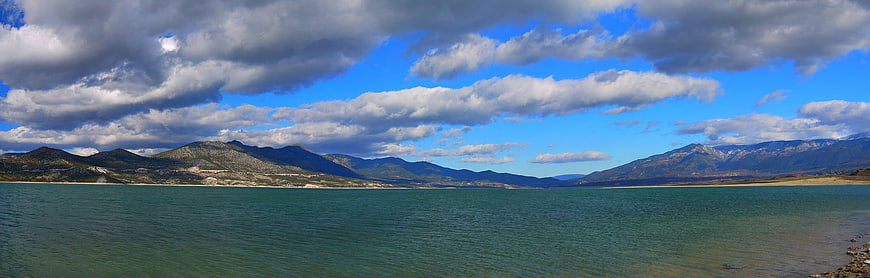 Panoramic view of a lake with mountains and cloudy sky