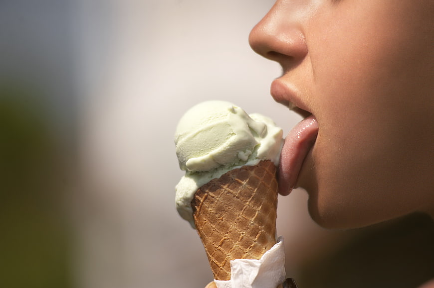 Close-up of woman licking green ice cream cone
