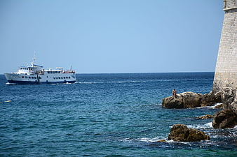Ferry boat sailing past stone tower on sunny summer day