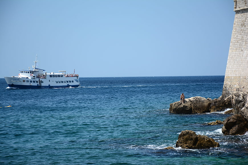 Ferry boat sailing past stone tower on sunny summer day