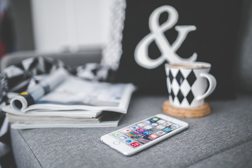 White smartphone and coffee cup on gray sofa