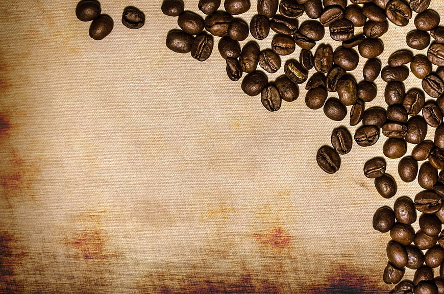 Roasted Coffee Beans Scattered on Textured Beige Linen Background