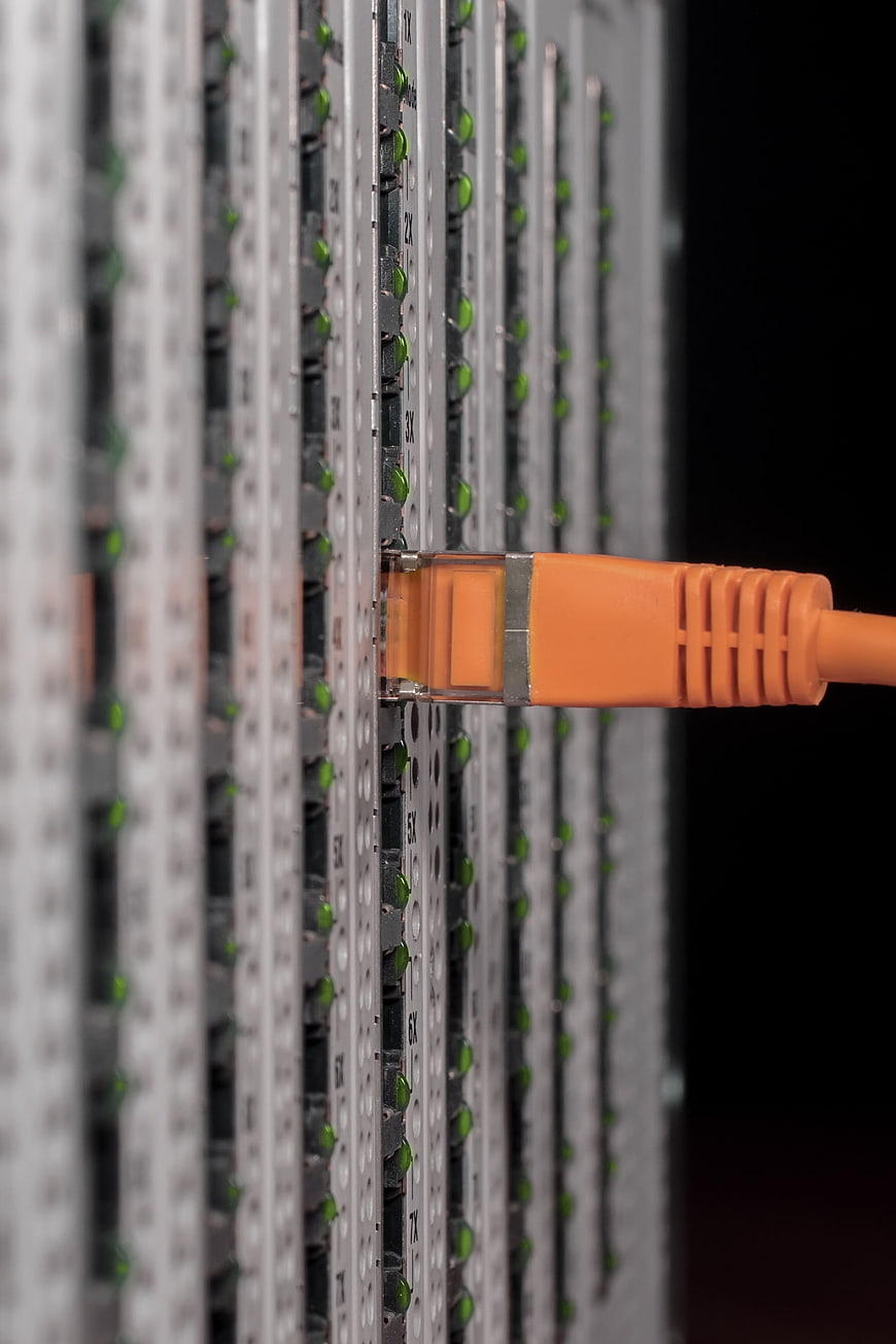 Close-up of orange ethernet cable plugged into network switch port