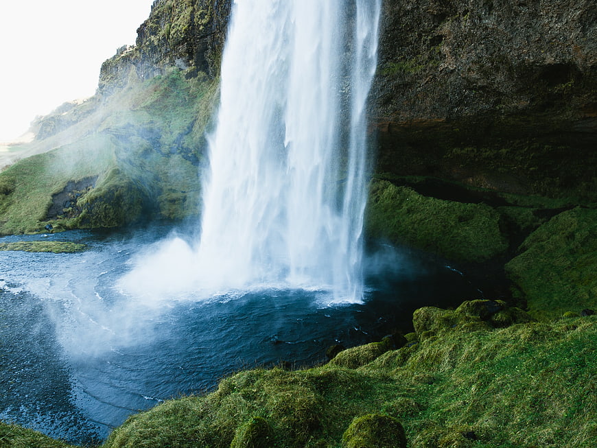 Majestic waterfall cascading into a pool surrounded by lush green cliffs