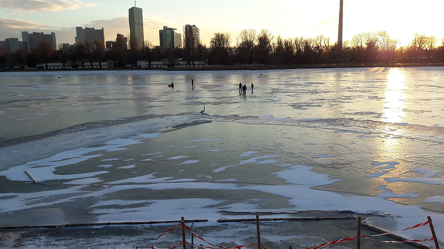 Wide view of frozen lake with city skyline at sunset