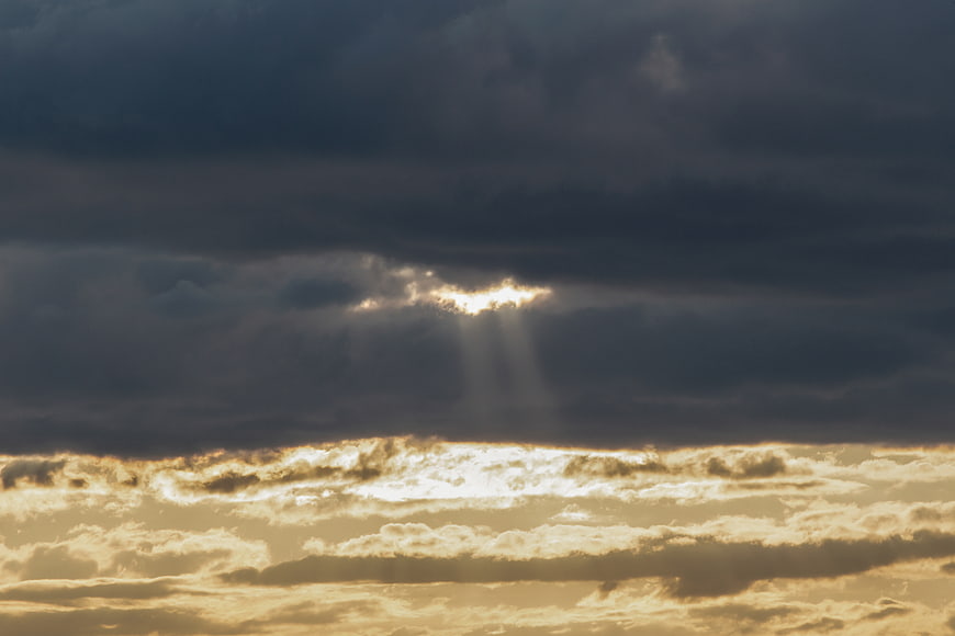 Dramatic Sunbeams Breaking Through Dark Storm Clouds