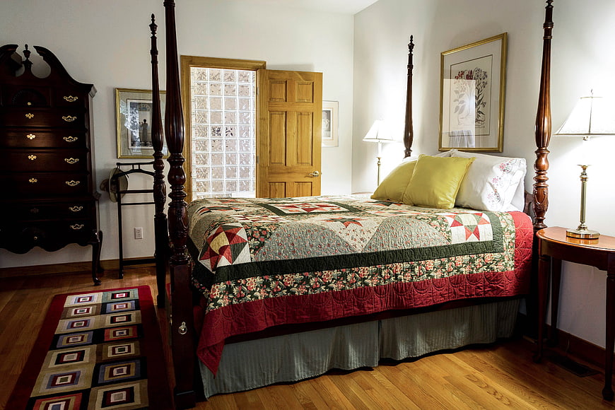 Traditional Bedroom Interior With Antique Four-Poster Bed And Patchwork Quilt