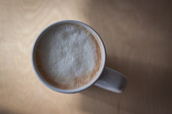 Top View of Frothy Cappuccino in White Mug on Wood