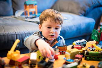 Young boy playing with toy trains on wooden table