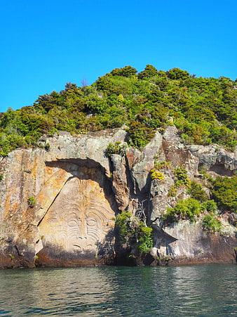 Maori rock carving on cliff face by the ocean
