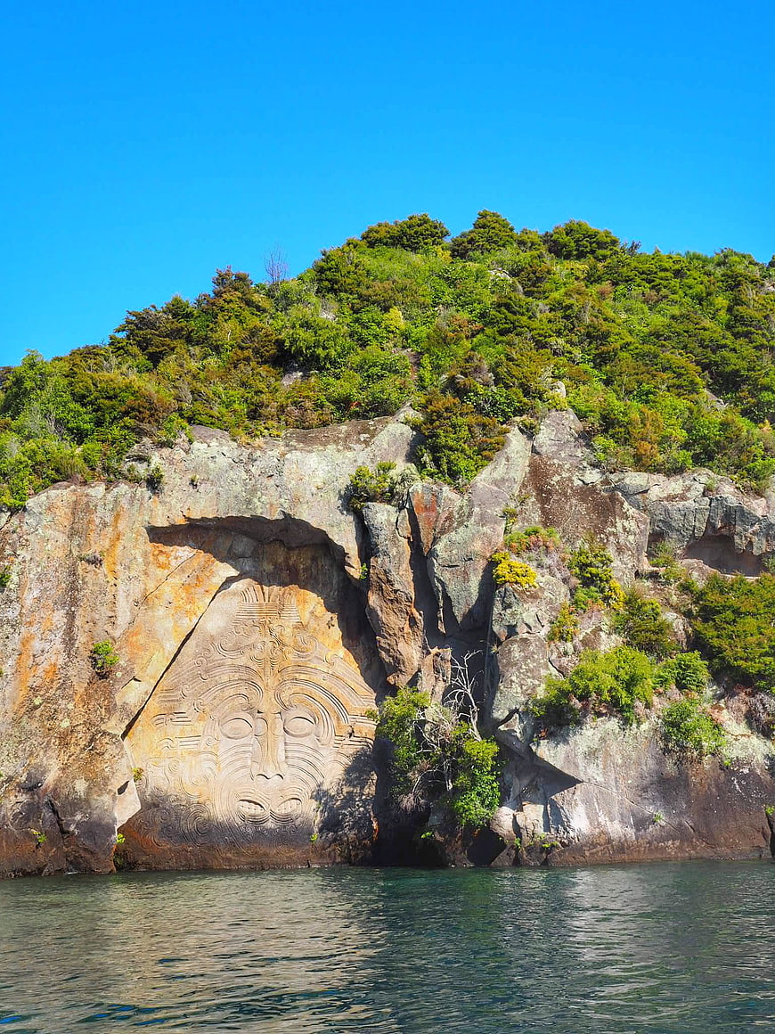 Maori rock carving on cliff face by the ocean