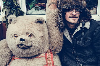 Man in fur hat posing with large bear mascot