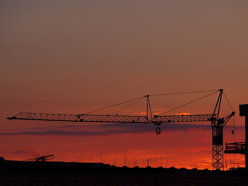 Silhouette of Construction Crane Against Vibrant Orange Sunset Sky