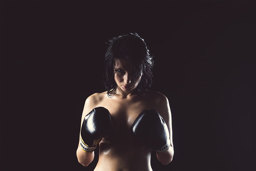 Female boxer in black gloves with dramatic studio lighting