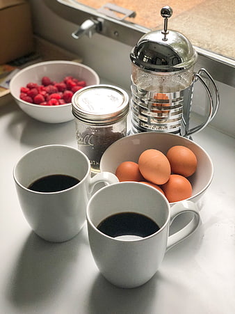 Healthy breakfast with coffee, eggs, and raspberries on kitchen counter