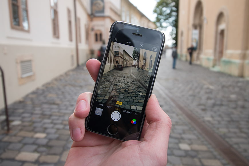 Hand holding smartphone taking photo of cobblestone street