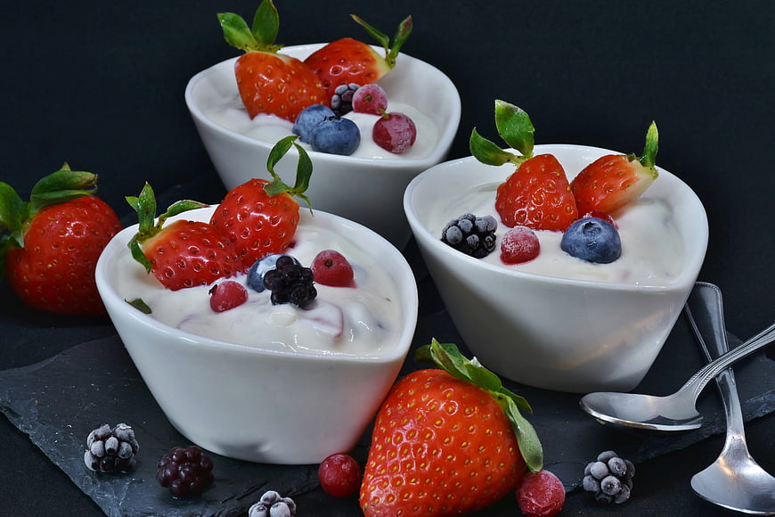 Fresh yogurt with strawberries and berries in white bowls