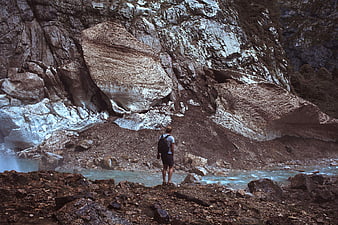 Hiker standing by glacial river in mountain valley