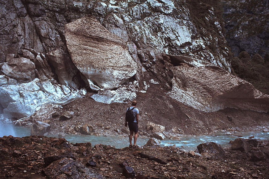 Hiker standing by glacial river in mountain valley