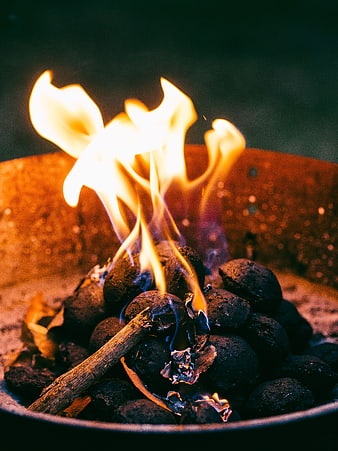 Close-up of burning charcoal briquettes with bright orange flames
