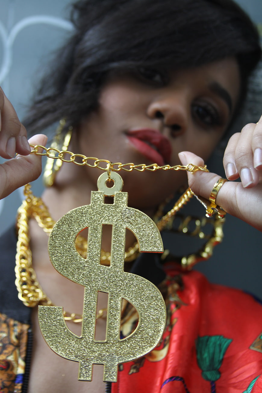 Woman holding large gold dollar sign pendant necklace