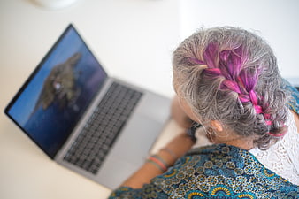 Senior woman with pink braided hair using laptop