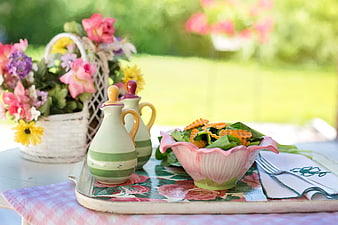 Fresh summer salad in pink bowl on floral tray with flowers