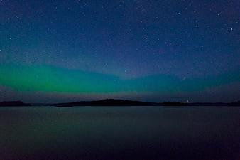 Aurora Borealis over a calm lake at night with stars