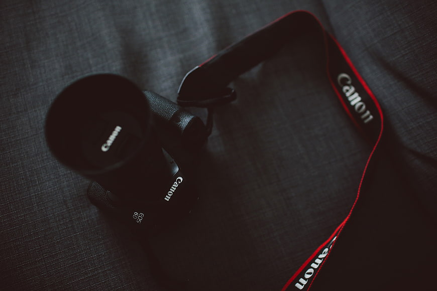 Black Canon DSLR Camera on Dark Textured Fabric