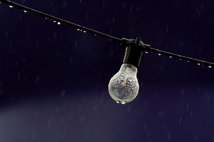 Unlit Light Bulb Hanging in Rain at Night