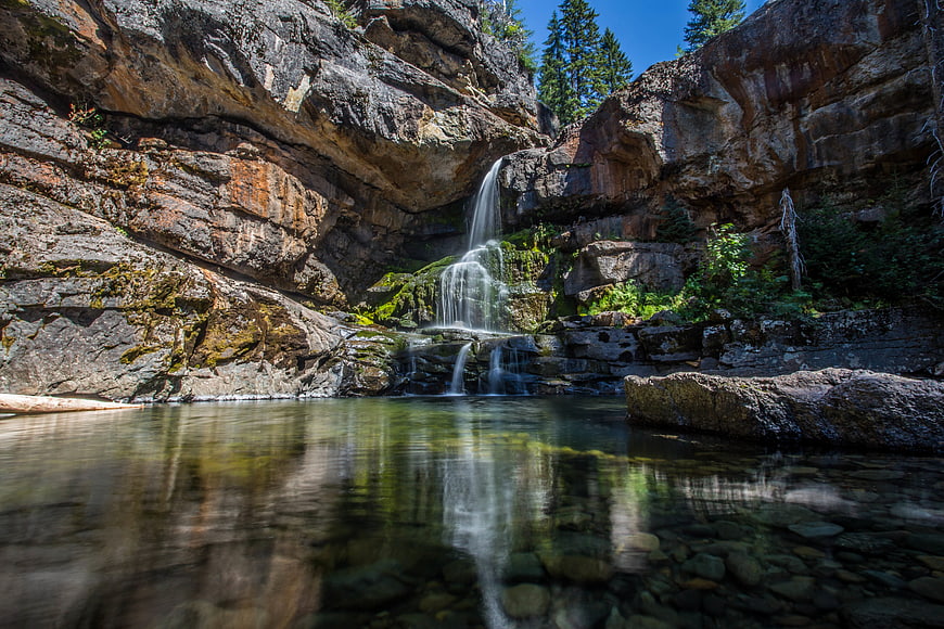 Serene waterfall cascading into a clear pool in a rocky canyon