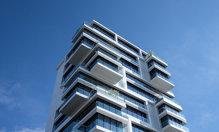 Modern White High-Rise Apartment Building Against Blue Sky