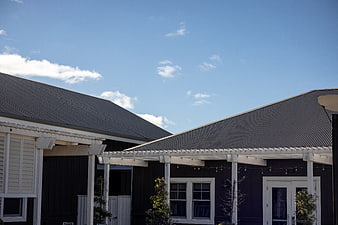 Modern Black House Exterior with Metal Roof and Blue Sky