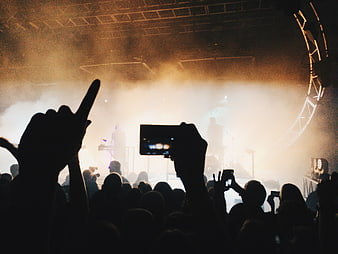 Silhouetted crowd recording live concert with smartphones