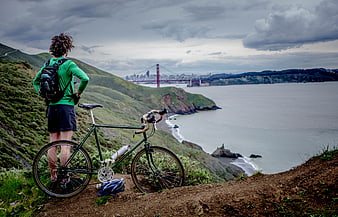 Cyclist overlooking Golden Gate Bridge from coastal trail