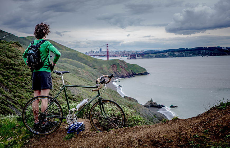 Cyclist overlooking Golden Gate Bridge from coastal trail
