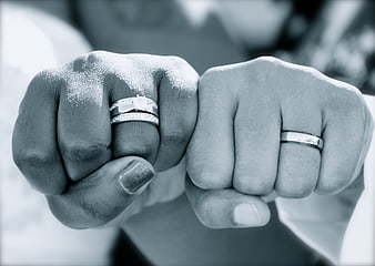 Close-up of two hands holding wedding rings in black and white