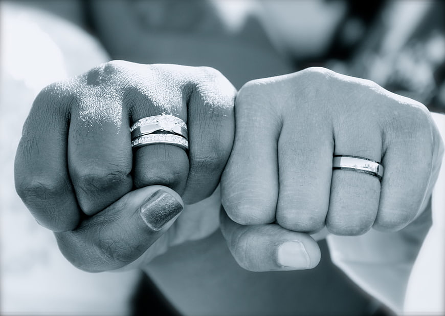 Close-up of two hands holding wedding rings in black and white