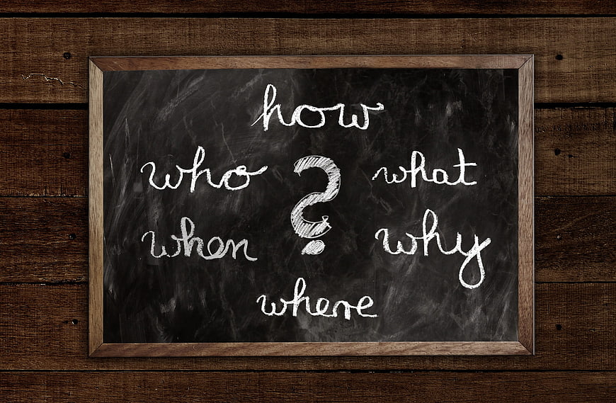 Chalkboard with Question Words on Rustic Wooden Background